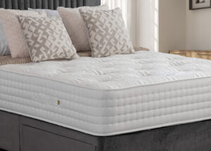 Apley Cashmere Ortho 2000 Pocket Sprung Mattress on a grey bed frame, decorated with beige patterned and cream pillows.