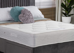 Image of 13.5g Bonnell coil spring Eden Rupert Mattress. The spring unit is enveloped in eight plush layers of sumptuous polyester fillings and insulator pads, promising not just exquisite comfort but also improved airflow. This ensures a cool, refreshing sleep. The mattress is on a divan base with pillows and soft furnishings.