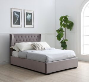 This image shows a king-size Kensington Ottoman Bed Velvet from Apleybeds.co.uk. The bed is upholstered in a luxurious soft grey velvet and has a softly winged headboard with Chesterfield-style button tufting. The black block feet add a touch of sophistication. The end-opening ottoman lifts on easy-glide gas strut mechanisms to reveal a spacious storage compartment.