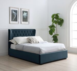 This image shows a king-size Kensington Ottoman Bed Velvet from Apleybeds.co.uk. The bed is upholstered in a luxurious soft ink velvet and has a softly winged headboard with Chesterfield-style button tufting. The black block feet add a touch of sophistication. The end-opening ottoman lifts on easy-glide gas strut mechanisms to reveal a spacious storage compartment.