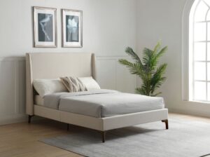 Image of a DENVER UPHOLSTERED BED STONE LIFESTYLE in asteria stone textured fabric. The bed is made of a stone colour fabric with a textured pattern. The headboard is tall and curved, and it has a button tufted detail. The bed legs are made of dark brown wood. There is a white pillow on the bed, and the floor is made of light brown hardwood.