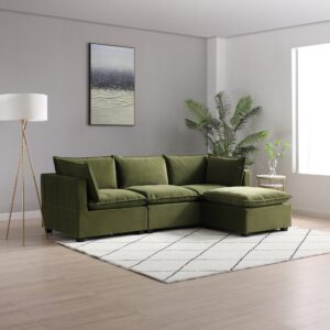 A luxurious Kyoto Moda corner sofa upholstered in rich olive velvet, featuring plush back cushions and a chaise for added comfort. The sofa is in a modern, well-lit room with light wooden flooring, accessorized with a geometric-patterned white and black area rug. A tall floor lamp with a golden stand to the left and a small round table with a potted plant to the right complement the contemporary aesthetic. The room is decorated with a large abstract canvas art piece above the sofa and a vibrant potted indoor palm, enhancing the relaxed yet sophisticated ambiance.