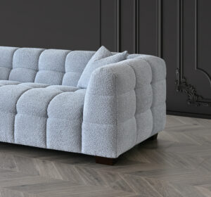 Detailed view of the armrest of the Tribeca Sofa in pearl bouclé fabric, resting on a wooden floor