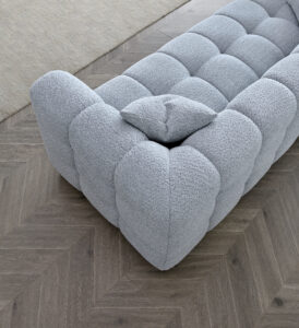 Close-up view of the Tribeca Sofa in pearl bouclé fabric with a grey shag rug