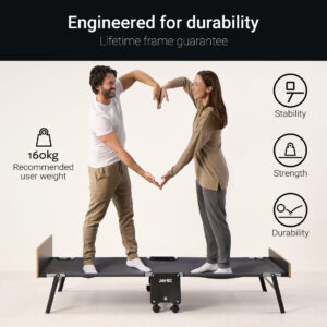 Two individuals stand on a Jay-Be folding bed, demonstrating its strength and durability. The image highlights the 160kg recommended user weight, along with icons representing stability, strength, and durability. Both individuals are making a heart shape with their arms, symbolising comfort and reliability.