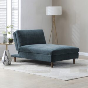 A modern navy blue chenille chaise sofa bed positioned in a bright, stylish living room with wooden flooring, a gold lamp, and a marble side table.