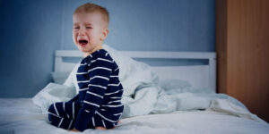 image of child crying on a bed