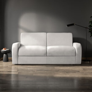 Modern three-seater Deco sofa in a light grey fabric, set against a dark, minimalist interior with a sleek floor lamp and side table.