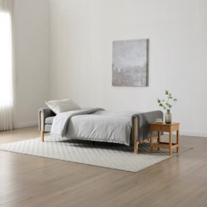 Thea Click Clack Sofa Bed in grey upholstery shown in bed position with minimalist decor.