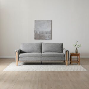 Thea Click Clack Sofa Bed in grey fabric with wooden arms, displayed in sofa position in a modern living space.