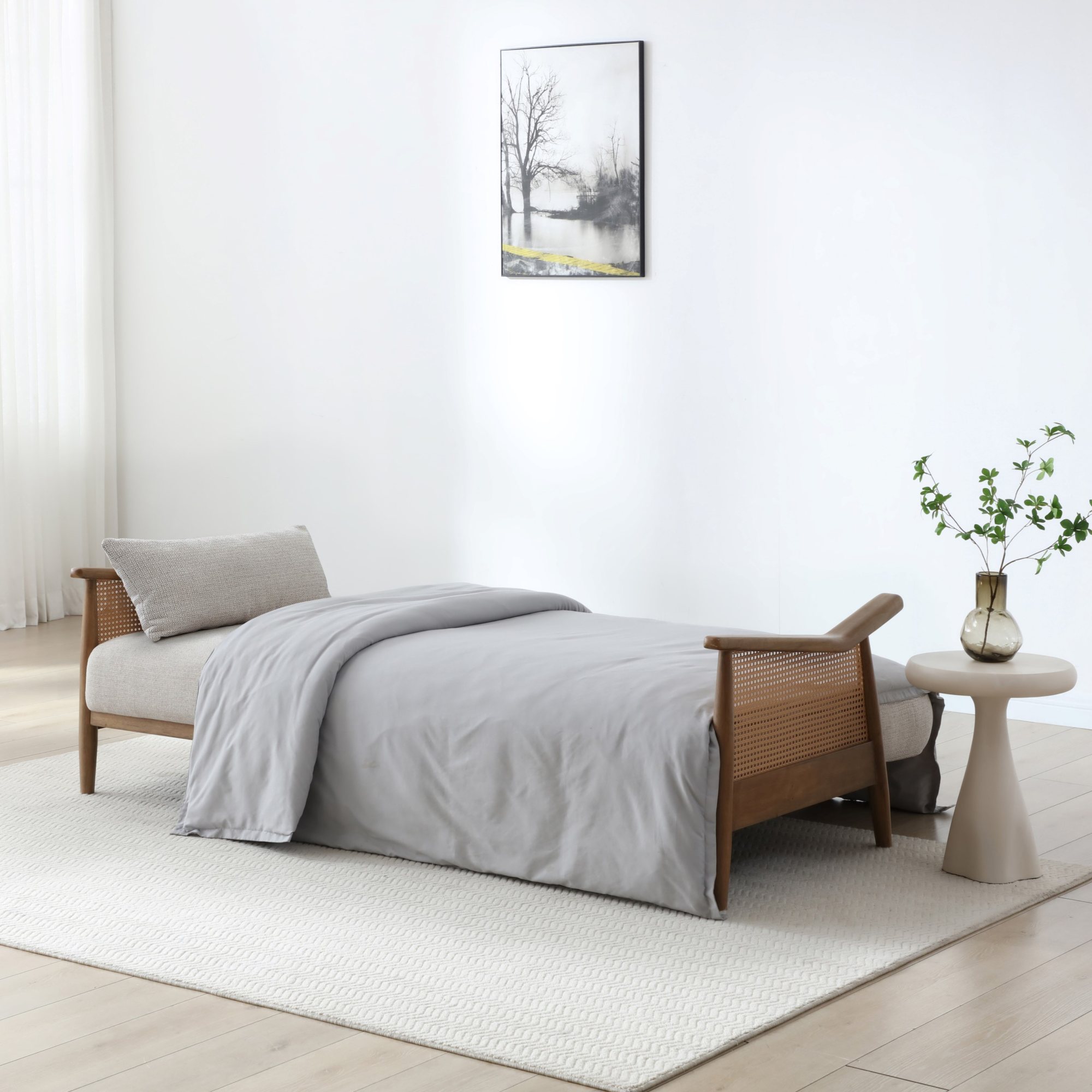 Zara Rattan Arm Sofa Bed made up as a bed with bedding in a living room