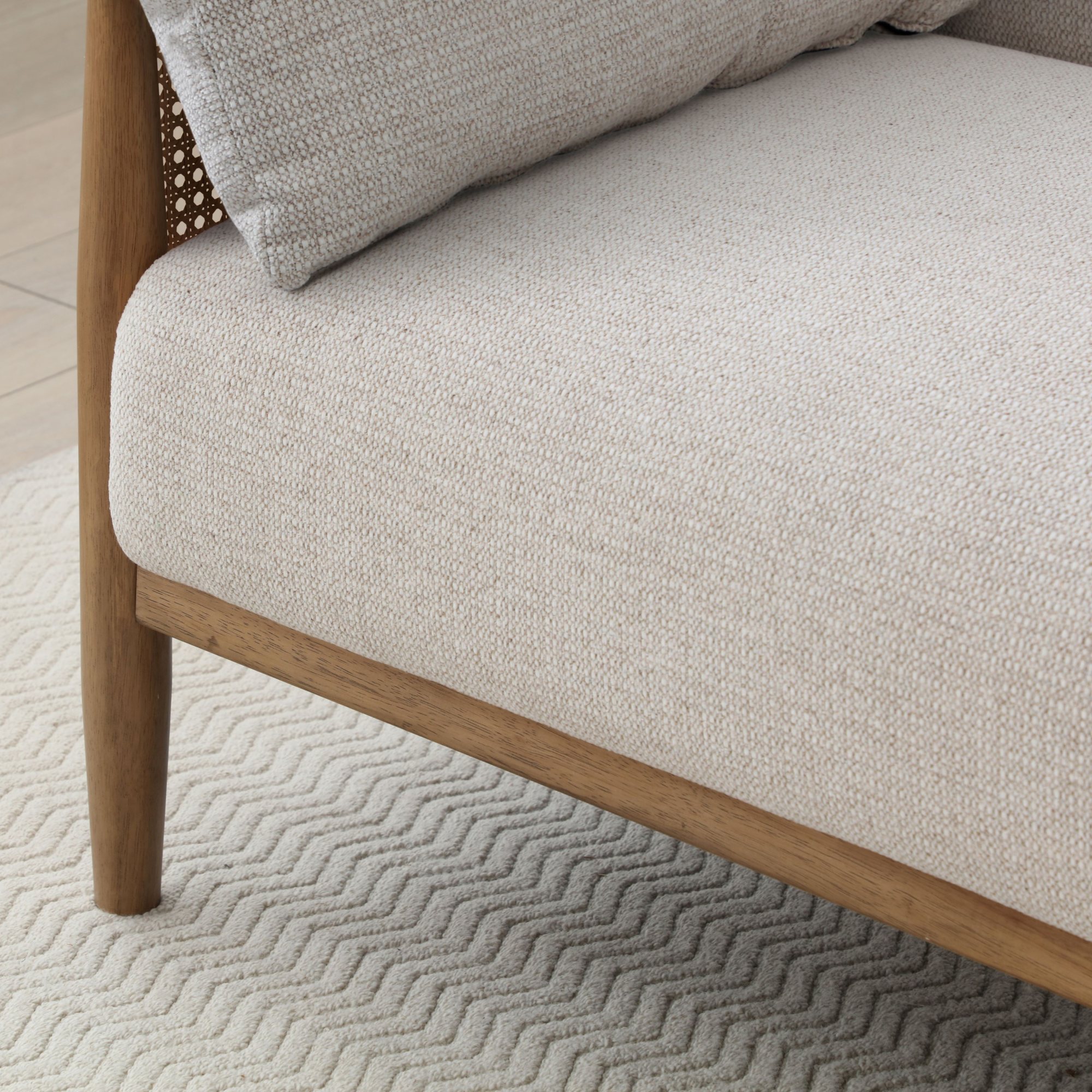 Close-up of the cane rattan arm panel and wooden frame on the Zara Sofa Bed