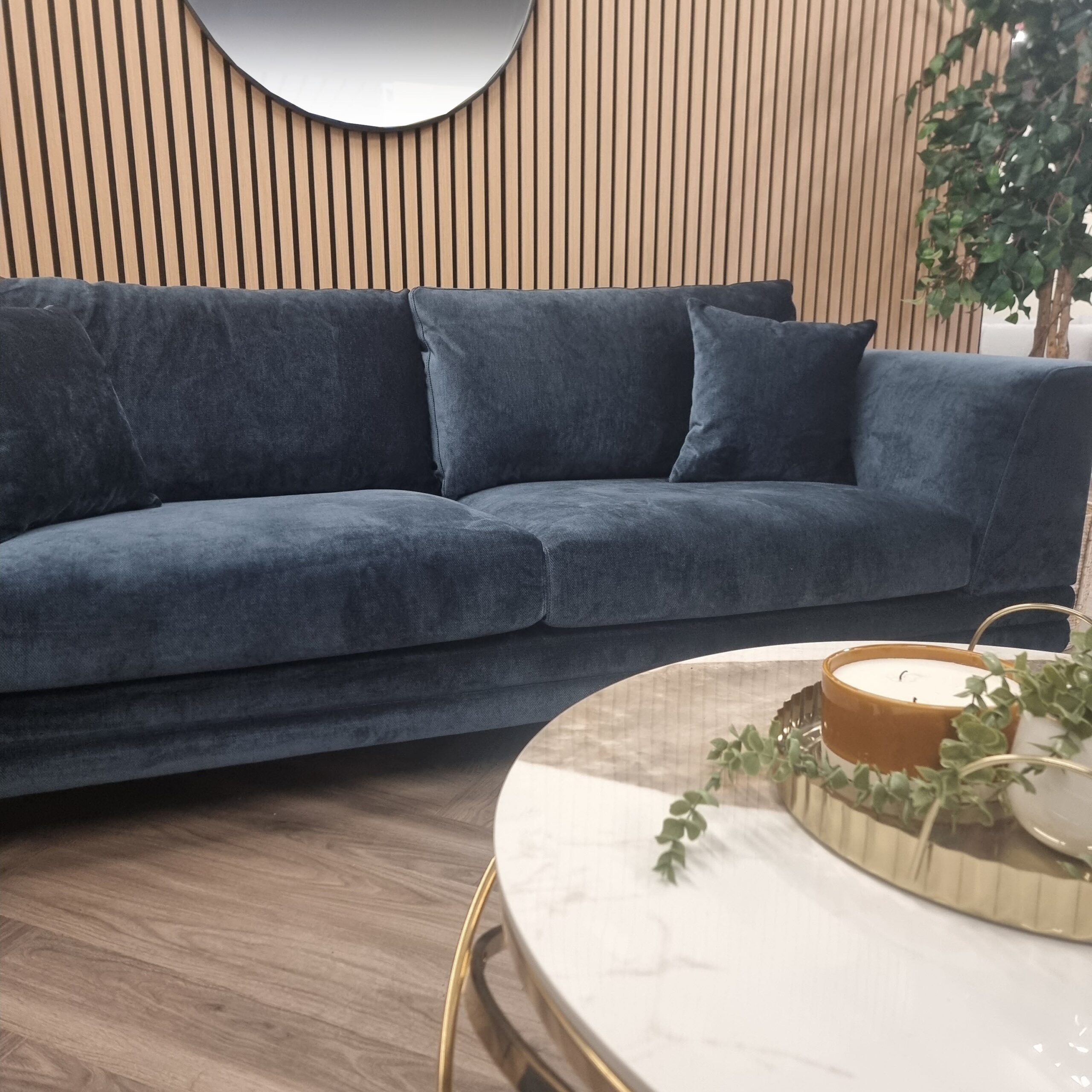 Lenox aegean blue velvet sofa in a showroom setting with a round marble coffee table