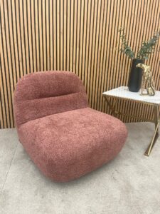 Miami swivel accent chair in blush orange boucle styled in a room with slatted wood panelling and a side table