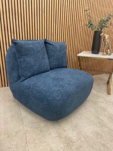 Miami swivel accent chair in navy blue boucle with two scatter cushions against slatted wood panelling