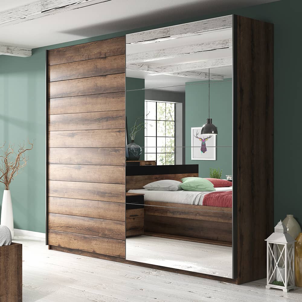 Beta Sliding Door Mirrored Wardrobe in Oak Monastery - shown in a bedroom setting, 221cm wide