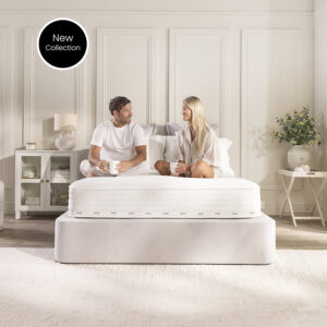 Couple sitting on the Jay-Be Pure Anti-Allergy pocket sprung mattress on a cream upholstered bed
