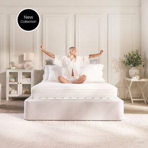 Woman stretching on the Jay-Be Pure Anti-Allergy Comfort Sprung mattress on a white upholstered bed in a bright panelled bedroom