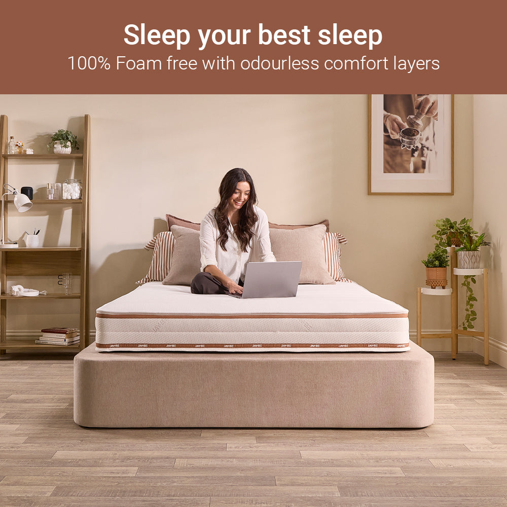 Woman working on a laptop sitting on the Ryze Deep Quilted mattress, foam-free with odourless comfort layers