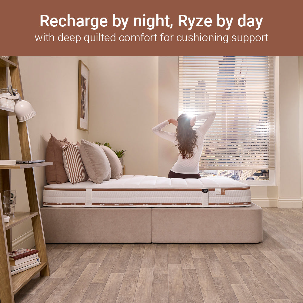 Woman stretching on a Jay-Be Ryze Deep Quilted sprung mattress in a sunny bedroom