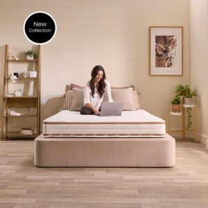Woman sitting cross-legged with a laptop on the Jay-Be Ryze Memory sprung mattress