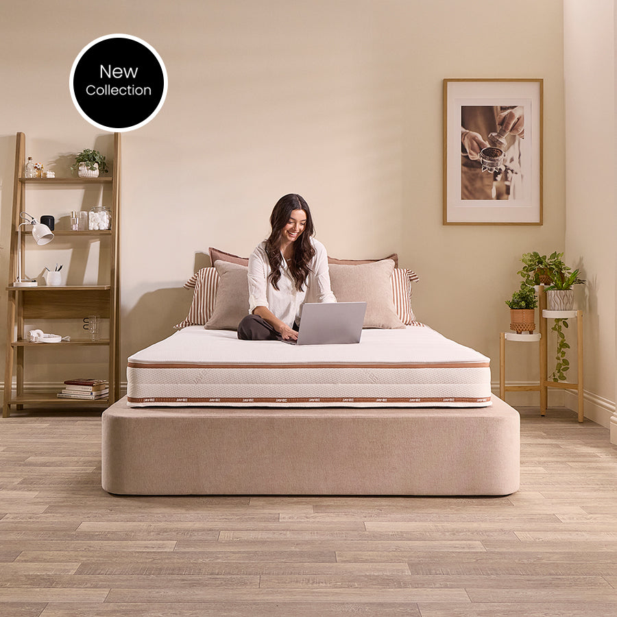 Woman sitting cross-legged with a laptop on the Jay-Be Ryze Memory sprung mattress