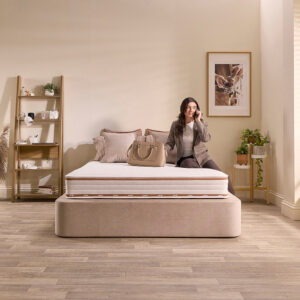 Woman sitting on the edge of a Jay-Be Ryze Memory mattress, showing the deep quilted top