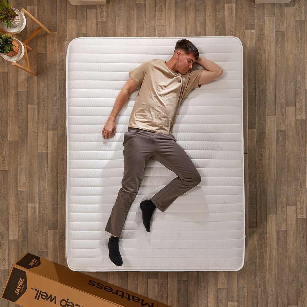 Man stretched out on the Jay-Be Ryze Memory mattress seen from above, next to its delivery box
